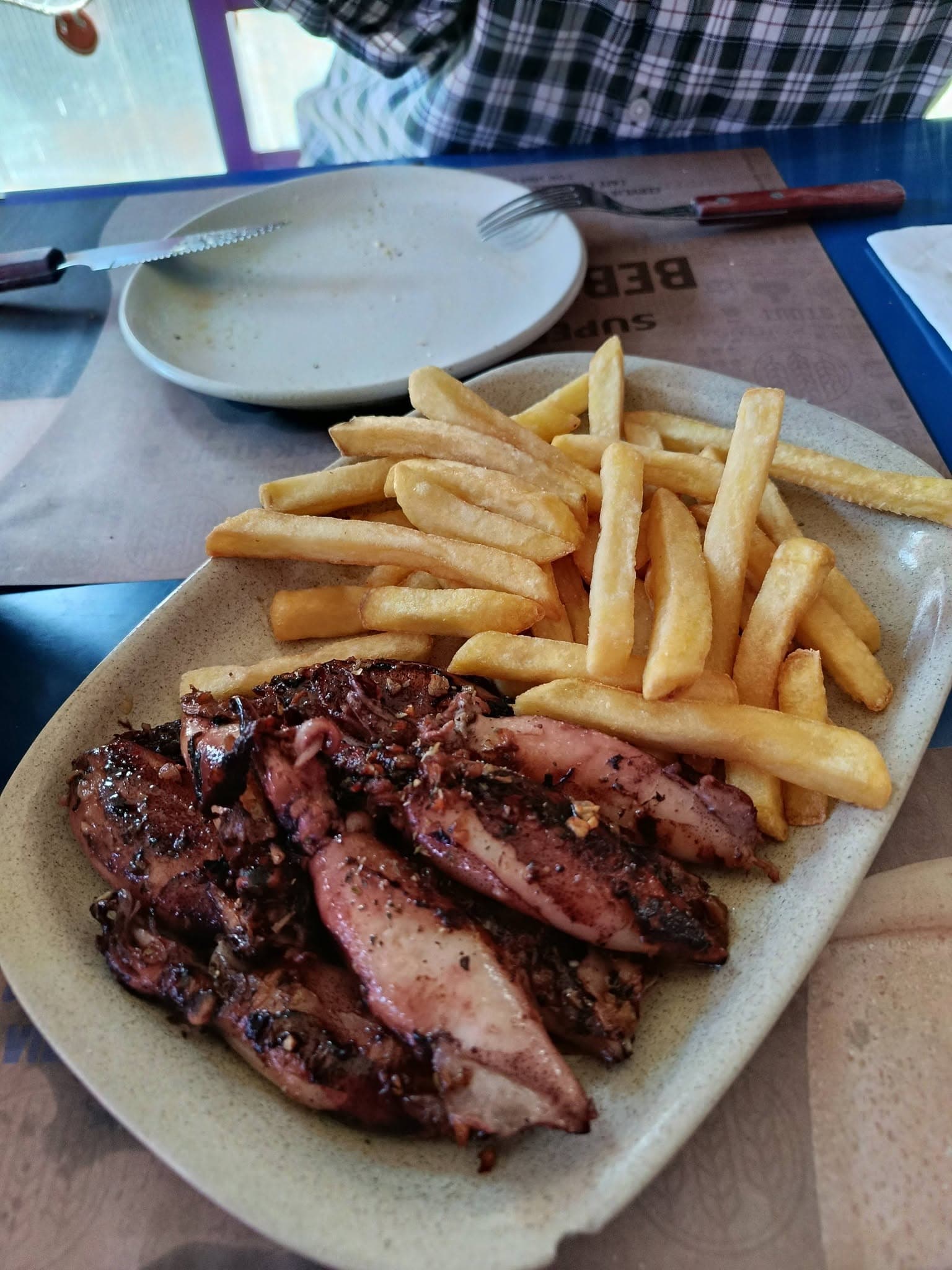 Lulas grelhadas com alho e pimenta numa travessa, com batata frita ao lado.